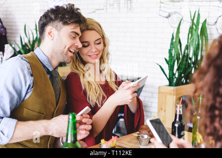 Selektiver Fokus der schönes Paar lächelnd und mit digitalen Geräten im Cafe Stockfoto