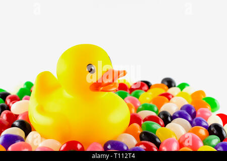 Nahaufnahme von einem Spielzeug Badeente mit Jelly Beans vor einem weißen Hintergrund umgeben. Landschaft abgeschnitten. Kopieren Raum über. Stockfoto