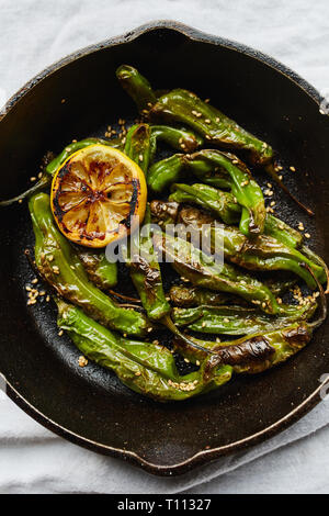 Shishito Paprika in einer gusseisernen Pfanne mit Sesamöl und Sesam verkohlt. Stockfoto