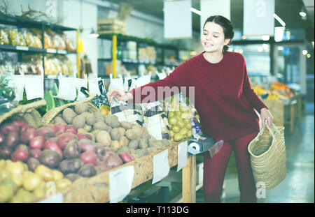 Junge Frau entscheidet, Kartoffeln, die in der pflanzlichen Marktplatz Stockfoto