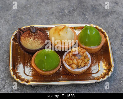 Exquisites Gebäck mit Nüssen, Pistazien und Kaffee auf einem goldenen Tablett Stockfoto