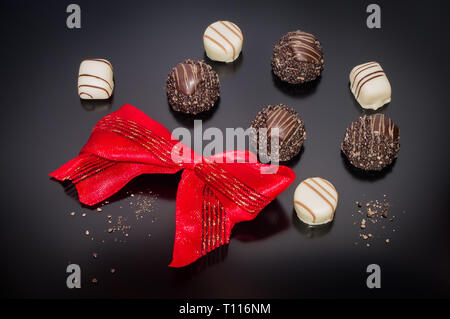 Schokolade Pralinen Trüffel mit Rot funkelnden gebunden Bogen Konfektion. Stockfoto