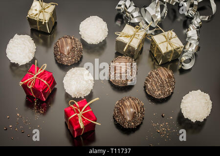 Schokolade mit Mandeln und Kokos Kugeln für den Weihnachtstag mit festliche Dekoration. 5 psc kleine Requisiten Weihnachten, geschenk. Stockfoto