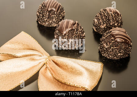 Vier Stücke Schokolade Trüffel mit Gold Ribbon Hintergrund. Stockfoto
