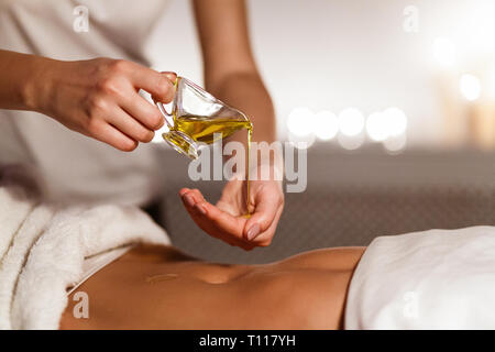 Masseur gießen Öl auf der Hand, die Vorbereitung auf die Massage Stockfoto