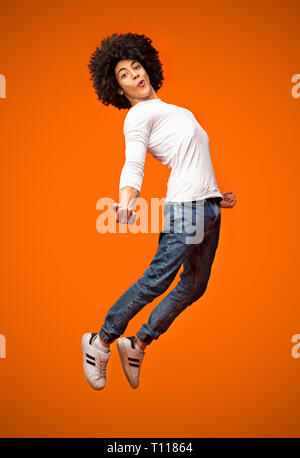 Aufgeregt, african-american man springen auf orangefarbenem Hintergrund Stockfoto