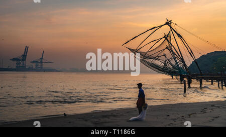 Einsamer Mann fischer Chinesische Fischernetze während des goldenen Stunden in Fort Kochi, Kerala, Indien sunrise Stockfoto