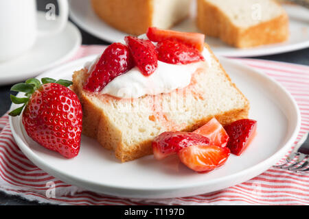 Teil der Engel essen Kuchen mit Sahne und Erdbeeren serviert. Stockfoto