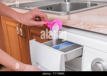 Frauenhände, kaffeeweißer in der Waschmaschine. Stockfoto