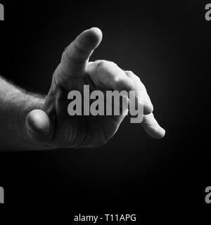 Schwarz/Weiß-Bild von der Hand des Menschen, der, auf einem schwarzen Hintergrund mit dramatischen Begrenzungslicht isoliert. Stockfoto