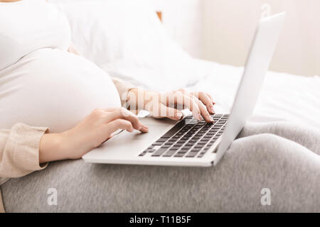 Schwangere Frau mit Baby blog auf Laptop Stockfoto