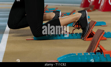 Action Bild einer weiblichen Athleten aus den Startlöchern für einen Sprint laufen auf einem Track Stockfoto