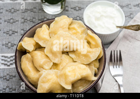 Vareniki mit Smetana (Schmand) serviert auf einem Tisch bereit zu essen Stockfoto