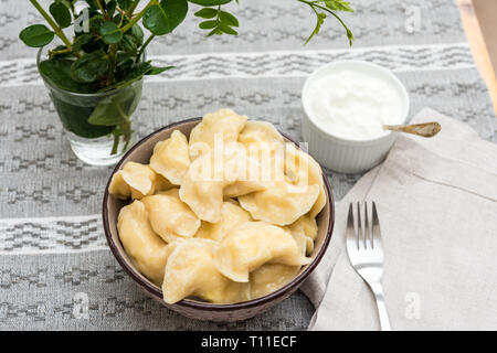 Vareniki mit Smetana (Schmand) serviert auf einem Tisch bereit zu essen Stockfoto