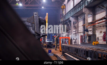 Industrielles Konzept. Ein Kran legen Sie die Detail auf dem Boden und der Mann Arbeiter es Stockfoto