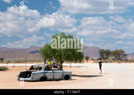 Ein altes rostiges Auto sitzt im Sand am Eingang des Solitaire Tankstelle, Restaurant und General Store Auf dem Weg in die Dünen bei Sossusvlei in Stockfoto