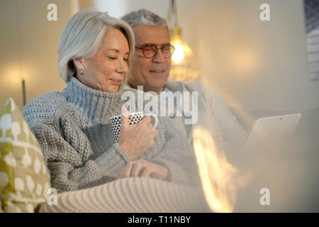 Senior Paar zu Hause entspannen auf der Couch mit Tablet Stockfoto