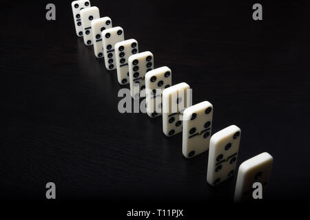 Domino Spielsteine in einer Reihe auf einem schwarzen Hintergrund Stockfoto