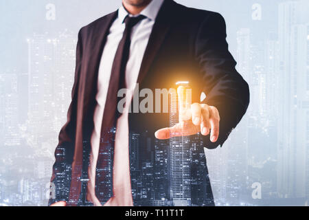 Man zeigt mit dem Finger auf virtuellen Bildschirm, mit modernen Skyline der Stadt - Immobilien Business Konzept Stockfoto