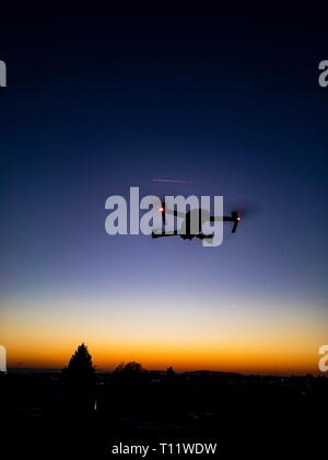 Die Silhouette einer Drohne (dji mavic pro) während des Fluges und im Hintergrund der Sonnenuntergang ist in einem schönen Blau Rot gesehen Stockfoto