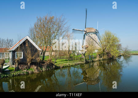 Typisch Holländischen ländliche Szene mit Bauernhof und Windmühle und Reflexion in den Kanal in der Front. Stockfoto