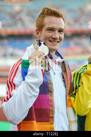 DELHI, INDIEN - 10. Oktober: Greg Rutherford (Silber) seine Medaille von Keith Davis auf dem Podium für lange der Männer springen, Commonwealth Games an Stockfoto