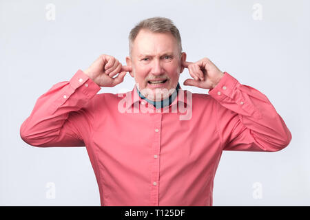 Ältere Menschen Ohren verstopfen mit Fingern. Studio schießen. Negative facial Emotion. Stockfoto