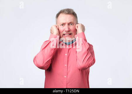 Ältere Menschen Ohren verstopfen mit Fingern. Studio schießen. Negative facial Emotion. Stockfoto