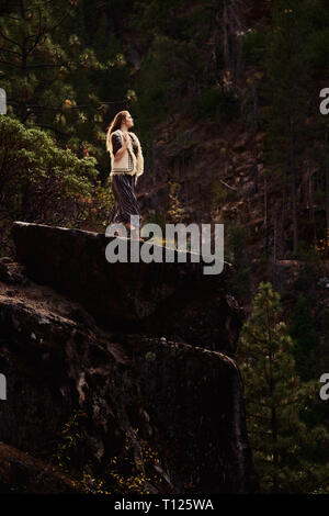 Eine selbstbewusste und abenteuerlustige junge Frau trägt einen Rock, Weste und Stiefel in den Sierra Nevada Bergen in Nordkalifornien allein. Stockfoto