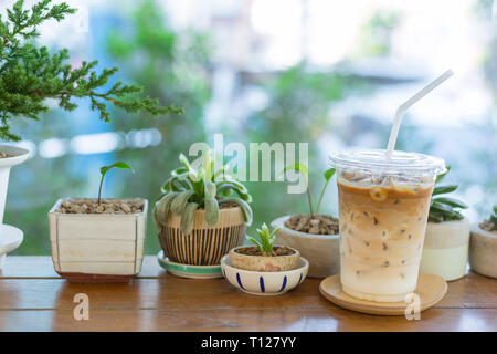 Ice latte Kaffee mit grün Natur auf hölzernen Tisch in Garden Cafe. Stockfoto