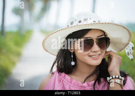 Asiatische Frau mit Sonnenbrille und Hut Stockfoto