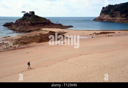 Frau Wanderer zu Fuß am Strand und in der Nähe von Portelet Turm auf einer felsigen Insel in der Gezeiten Portlet Bay, Saint Brélade Pfarrei auf der Insel Jersey, Channel Isles. Stockfoto