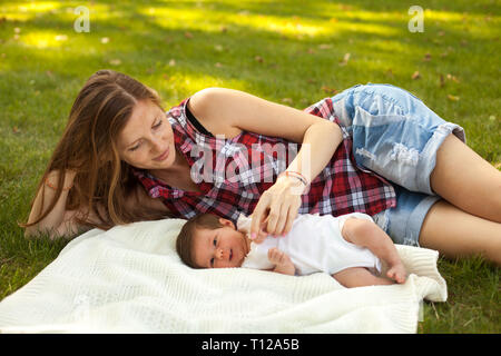 Mutter mit newborb Baby Mädchen liegt auf Gras Stockfoto