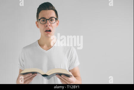 Nerd mit Brille und einem weißen T-Shirt ist ein Buch auf einem weißen Hintergrund. Ein Mann mag Bücher zu lesen Stockfoto