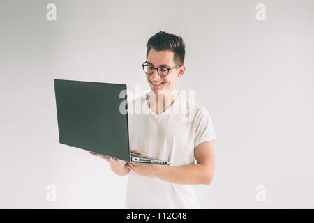 Mann mit Laptop Computer isoliert auf Grau. Nerd eine Brille trägt Stockfoto