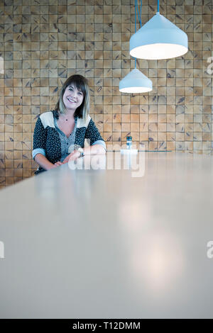 Eine junge Frau stellt an einem Tisch in einem Cafe/Restaurant Stockfoto