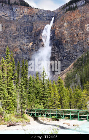 Fußgängerbrücke über Kicking Horse River zu den mächtigen Takakkaw Falls in den Yoho Nationalpark in der Nähe von Feld, British Columbia, Kanada. Der Gletscher - FBI-Wasser Stockfoto