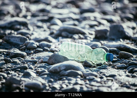 Plastikflasche liegt auf dem steinigen Strand, Umweltverschmutzung Stockfoto