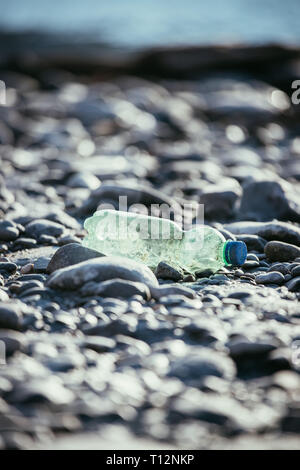 Plastikflasche liegt auf dem steinigen Strand, Umweltverschmutzung Stockfoto