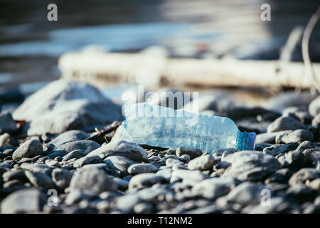 Plastikflasche liegt auf dem steinigen Strand, Umweltverschmutzung Stockfoto