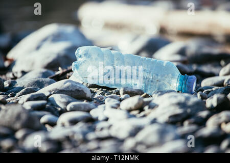 Plastikflasche liegt auf dem steinigen Strand, Umweltverschmutzung Stockfoto