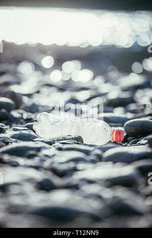 Plastikflasche liegt auf dem steinigen Strand, Umweltverschmutzung Stockfoto