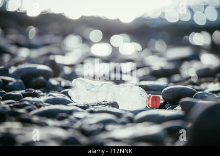 Plastikflasche liegt auf dem steinigen Strand, Umweltverschmutzung Stockfoto