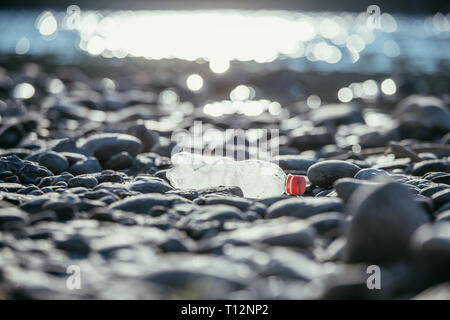 Plastikflasche liegt auf dem steinigen Strand, Umweltverschmutzung Stockfoto