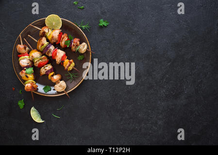 Gegrilltes Hähnchen und Gemüse Spieße mit Paprika, Zucchini, Zwiebel und Pilze auf schwarzen Hintergrund, Ansicht von oben, kopieren. Fleisch und Gemüse Stockfoto