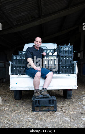 Ein echter Milch Mann steht auf seine Milch schweben mit Milchflaschen in einer Kiste Stockfoto