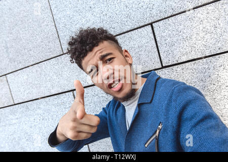 Junge afrikanische amerikanische Mann stehend auf Betonwand unter selfie Foto zeigen auf Kamera cool schließen isoliert - oben Stockfoto