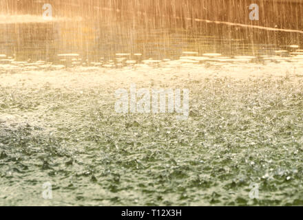 Tropfen auf der Wasseroberfläche. Die Regentropfen fallen auf der grünen Fläche des Wassers. Vintage stilisiert. Bewegungsunschärfe. Stockfoto