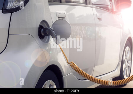 3D-Rendering von elektrischen Auto oder Fahrzeug an der Ladestation aufgeladen mit Kabel oder Ladegerät für ökologische und nachhaltige Energie Stockfoto