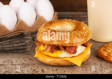 Sandwich Frühstück mit Zutaten im Hintergrund. Bagel, Ei, Käse und Speck. Stockfoto